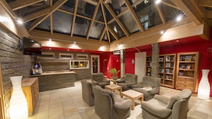 A spacious living area with a high ceiling and skylight, furnished with sofas and a coffee table, and a red accent wall.
