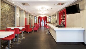 A modern bar area with red bar stools, a white counter, and a television mounted on the wall.