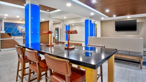 A modern dining area with a central table, wooden chairs, and a sofa. - Holiday Inn Express & Suites Houston West - Katy by IHG (Katy)