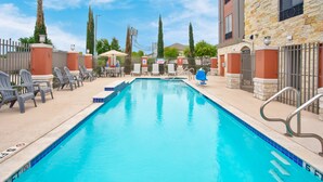 A swimming pool with lounge chairs and a stone building in the background. - Holiday Inn Express & Suites Houston West - Katy by IHG (Katy)