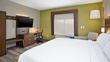 Una habitación de hotel con cama, escritorio, silla, televisión y ventana.