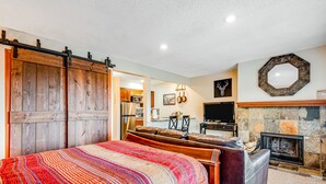 Un dormitorio con una cama grande, chimenea, televisor y una puerta corrediza de estilo rústico.