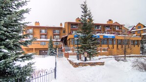 Un hotel de varios pisos con fachada nevada, una escalera visible y un letrero que indica un restaurante.