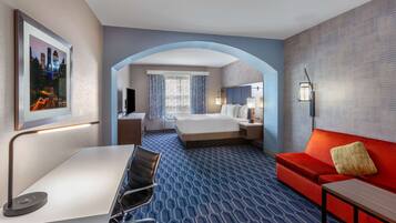 Habitación de hotel con cama, escritorio, sofá rojo y vista panorámica de la ciudad.