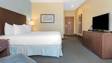 Una habitación de hotel con una cama grande, televisión, cómoda y un cuadro en la pared.