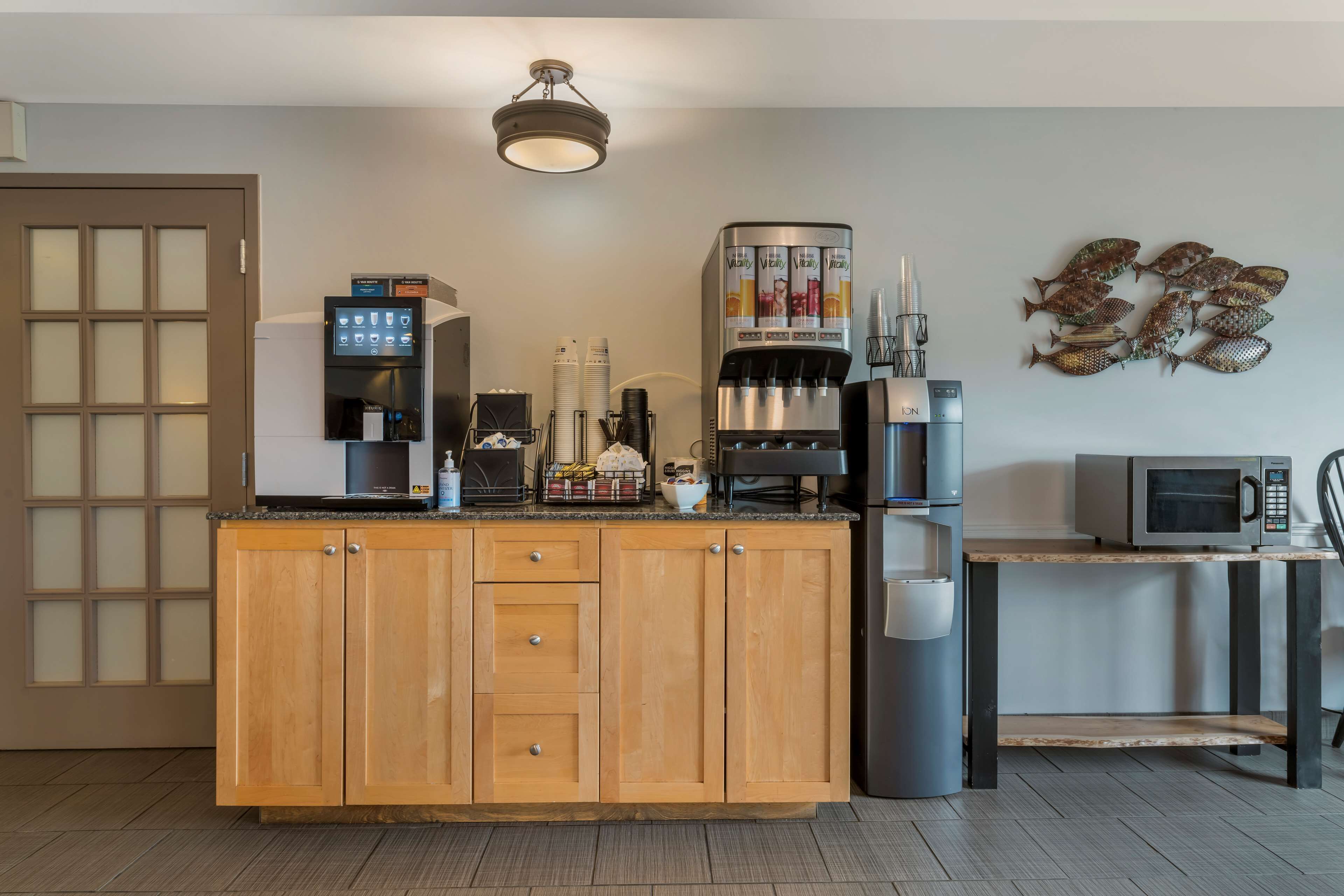 A modern kitchen with wooden cabinets, a built-in coffee machine, a microwave, and a refrigerator.