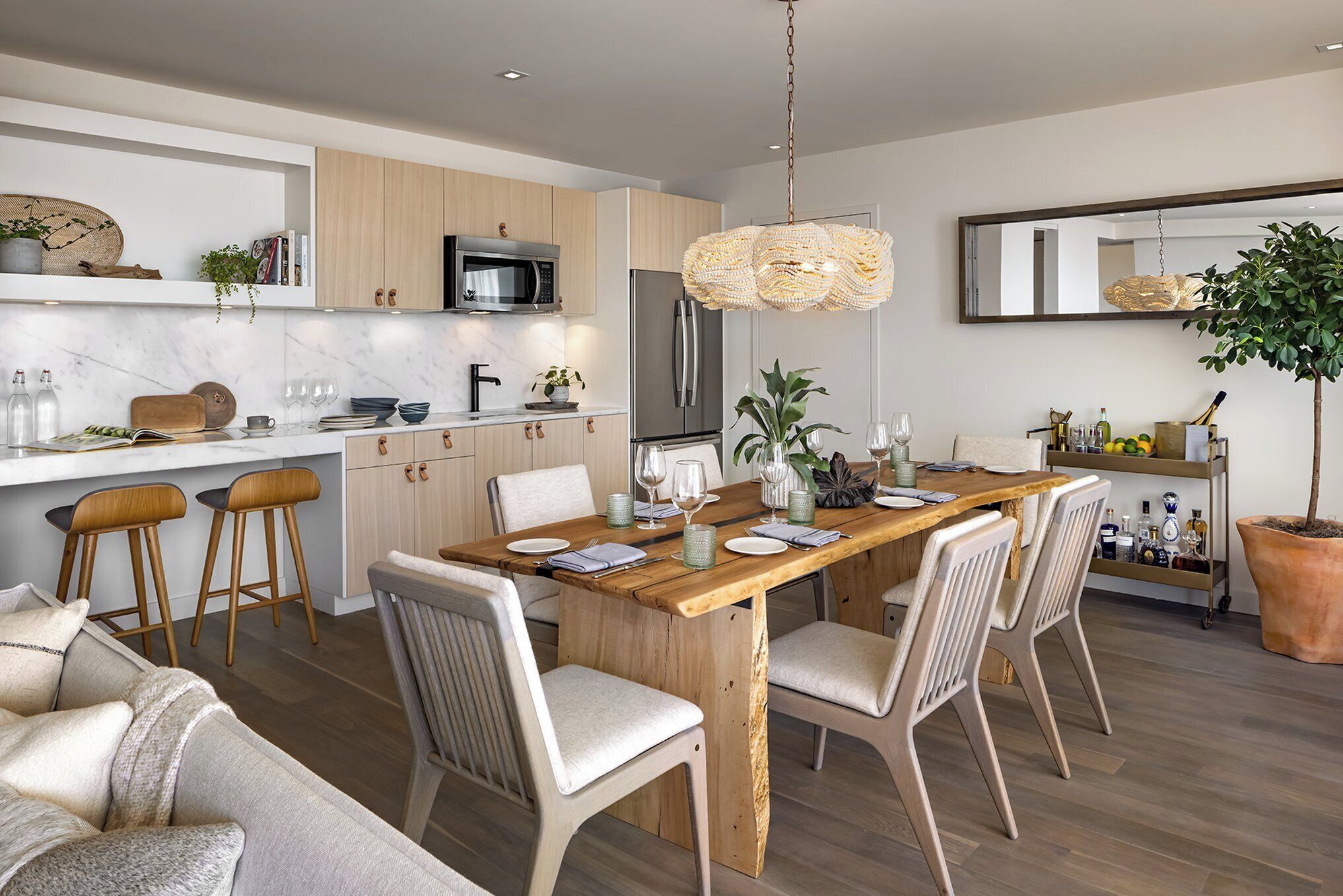 A modern kitchen with wooden cabinets, a stainless steel refrigerator, and a dining area with a wooden table and chairs.