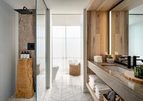 A modern bathroom with a shower, a wooden vanity, and a large mirror.