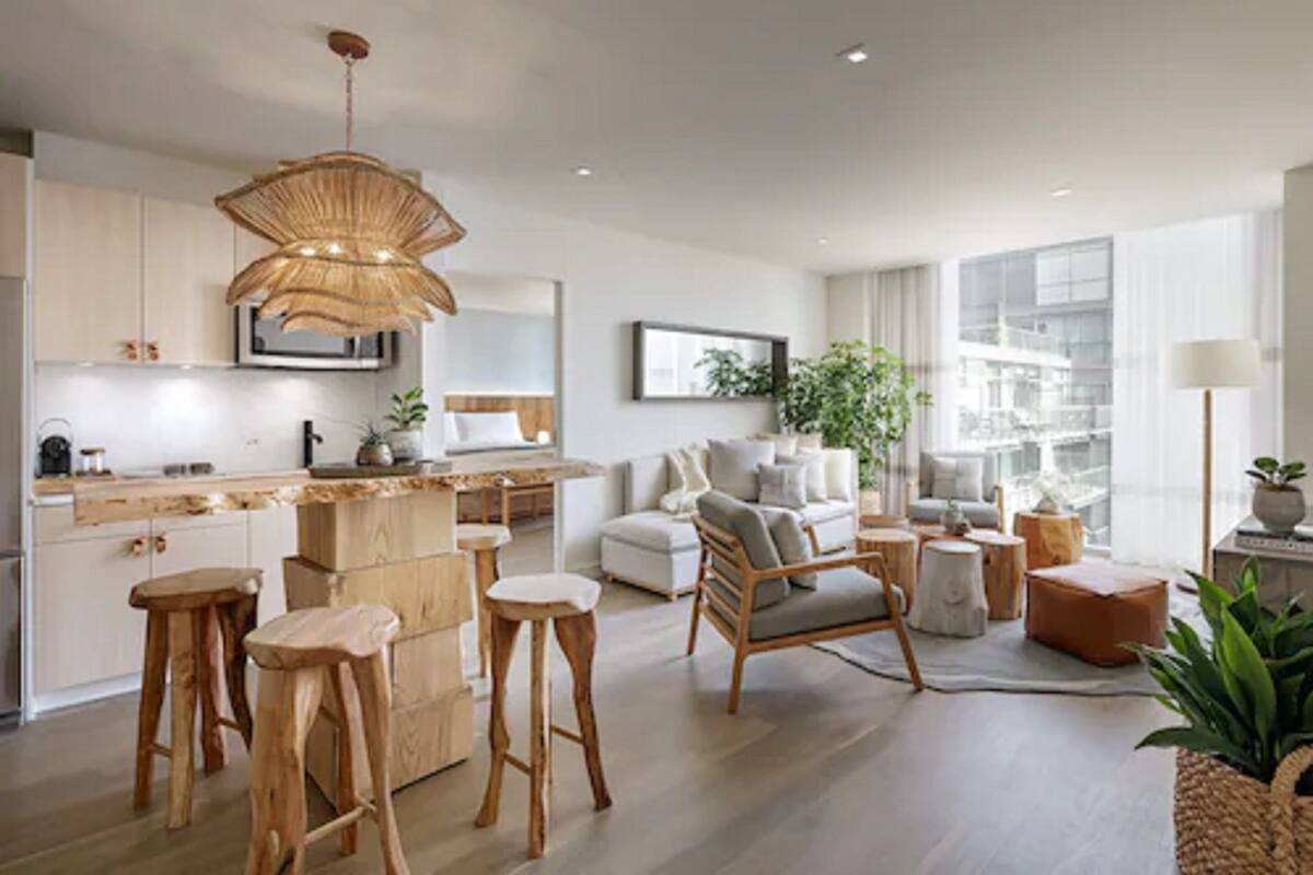 Une cuisine moderne avec des tabourets en bois, un coin repas avec un canapé blanc et une grande fenêtre offrant une vue sur la ville.