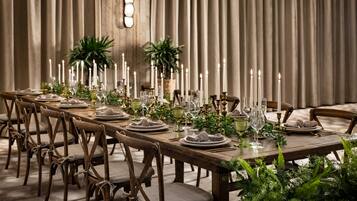 A long dining table set with candles, plates, glasses, and greenery.