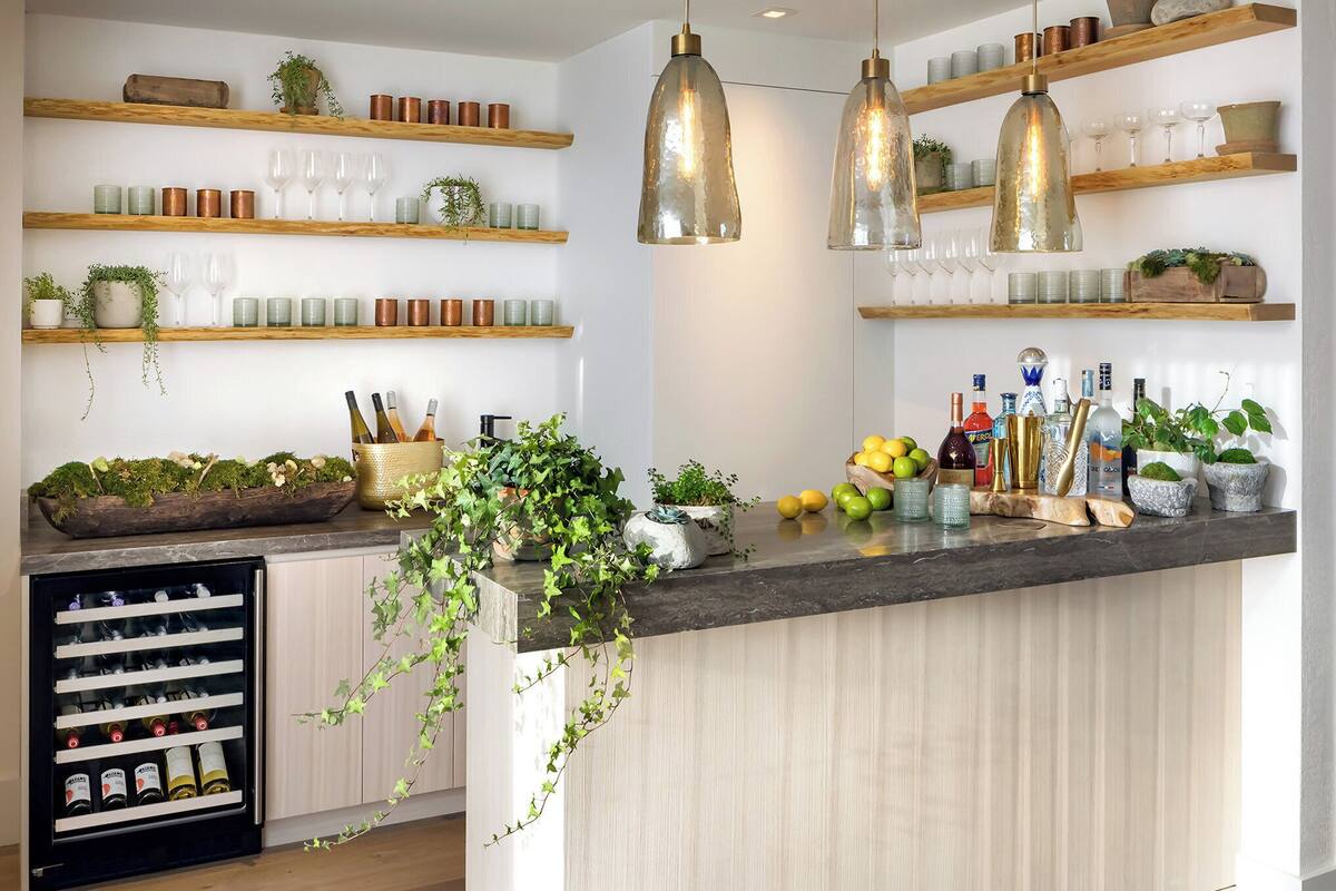 Une cuisine moderne dotée d’étagères en bois, de luminaires suspendus, d’un réfrigérateur à vin et d’une variété d’ustensiles de cuisine.