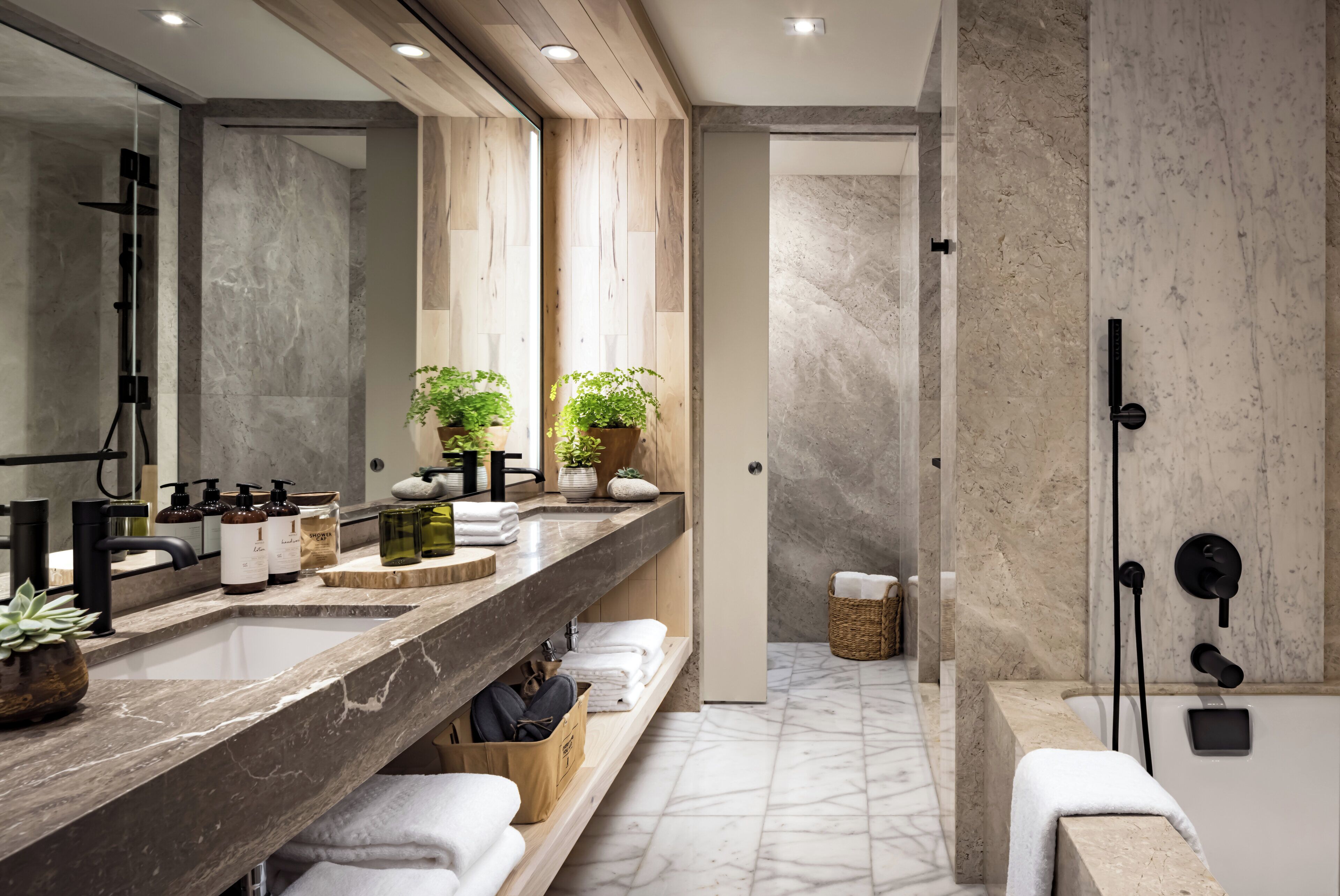 A modern bathroom with a large mirror, dual sinks, a shower, and a wooden vanity.