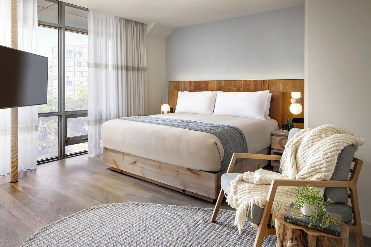 Une chambre avec un grand lit, des lampes de chevet, une télévision et une vue sur l’extérieur.