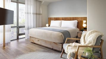 Un dormitorio con una cama grande, lámparas de noche, un televisor y vistas al exterior.