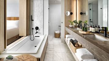 A modern bathroom with a large bathtub, a wooden vanity with a mirror, and a shower area.