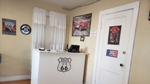 A reception desk with Route 66 signage, a door with a vintage gas pump sign, and various Route 66 memorabilia on the walls. - Deluxe Inn Motel (Seligman)