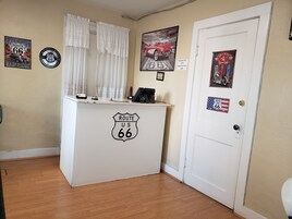 A reception desk with Route 66 signage, a door with a vintage gas pump sign, and various Route 66 memorabilia on the walls.