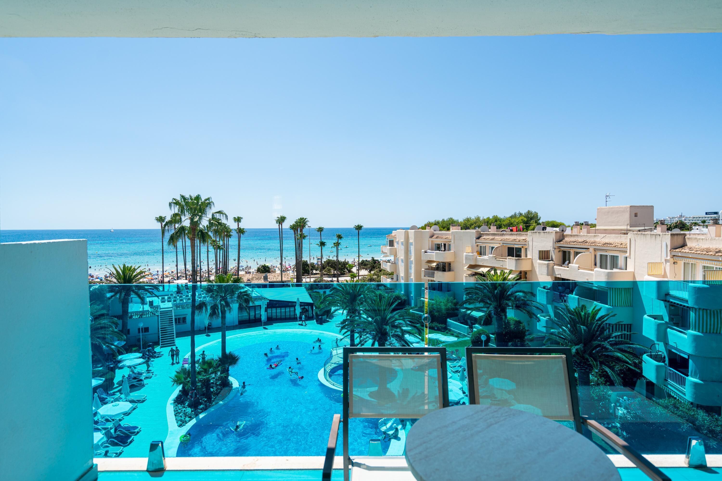 Un resort con piscina, palmeras y vista al océano.