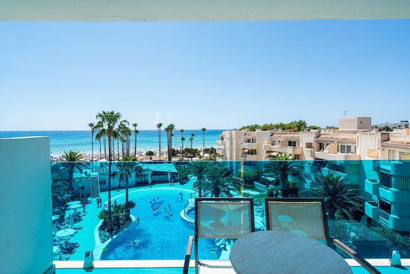 Un resort con piscina, palmeras y vista al océano.
