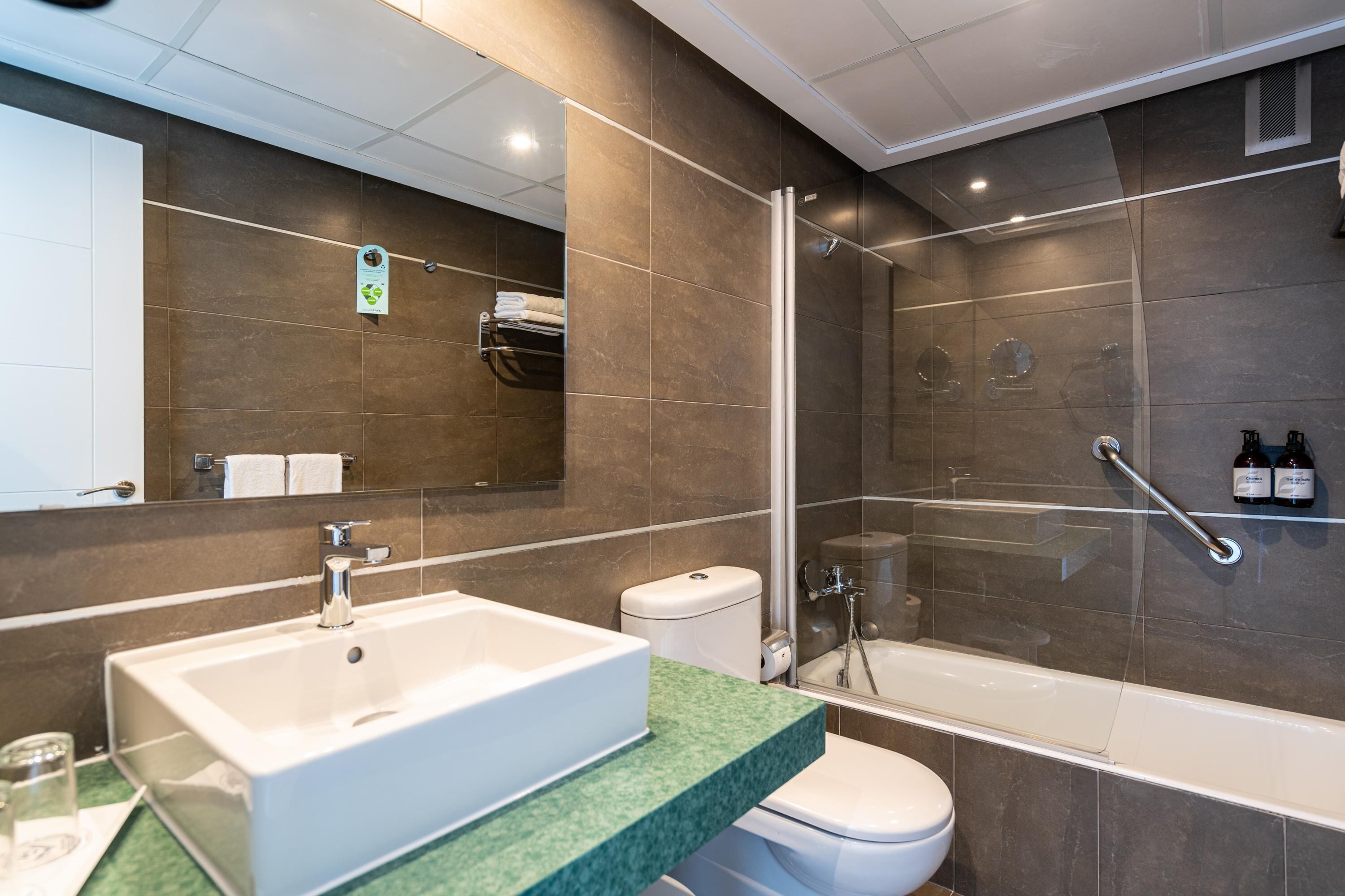 Un baño moderno con un lavamanos espacioso, inodoro y ducha a ras de suelo.