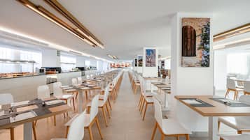 Un comedor moderno con mesas largas, sillas blancas y un pasillo central.