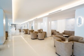 Un moderno vestíbulo de hotel con un diseño espacioso, con varias zonas de estar y una estética limpia y minimalista.