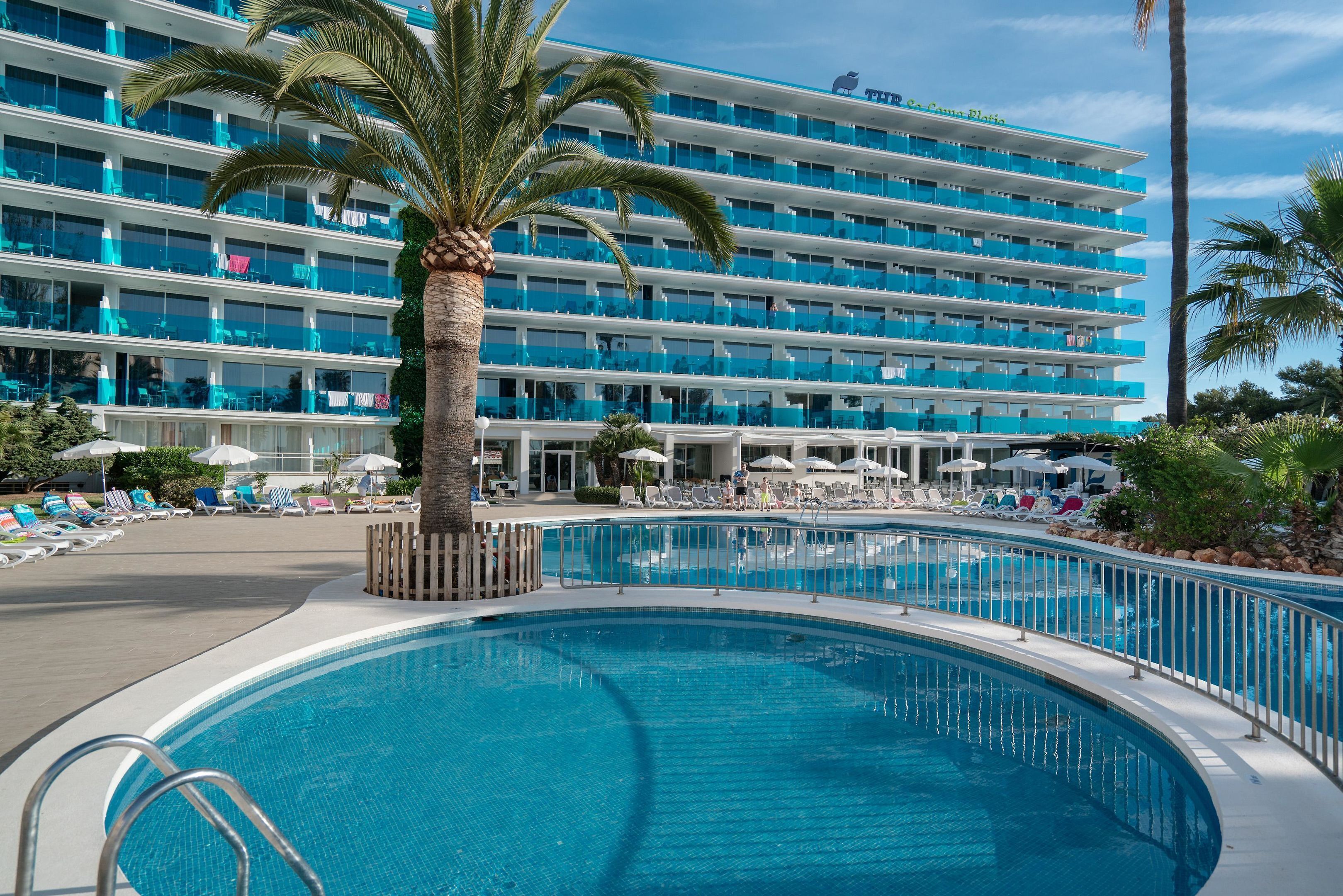 Ett hotell med en stor pool, flera balkonger och solstolar.