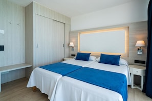A double bed with blue bedspreads, two bedside tables with lamps, a wooden wardrobe, and a wall-mounted light fixture. - Hotel THB Sa Coma Platja (Sant Llorenc des Cardassar)