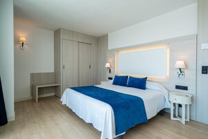 Un dormitorio moderno con una cama grande, mesitas de noche, un banco y un armario.