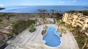 Un resort con una piscina grande, palmeras y vistas al océano.