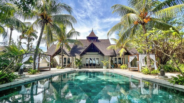 A pool area with a clear view of a building with a peaked roof and multiple windows. - Maradiva Villas Resort & Spa (Flic-en-Flac)