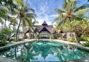 A pool area with a clear view of a building with a peaked roof and multiple windows. - Maradiva Villas Resort & Spa (Flic-en-Flac)