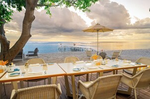 Un espacio para comer frente al mar, con una mesa dispuesta para cuatro.