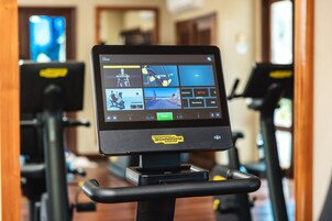 Una cinta de correr con pantalla digital que muestra diferentes opciones de entrenamiento y un panel de control.