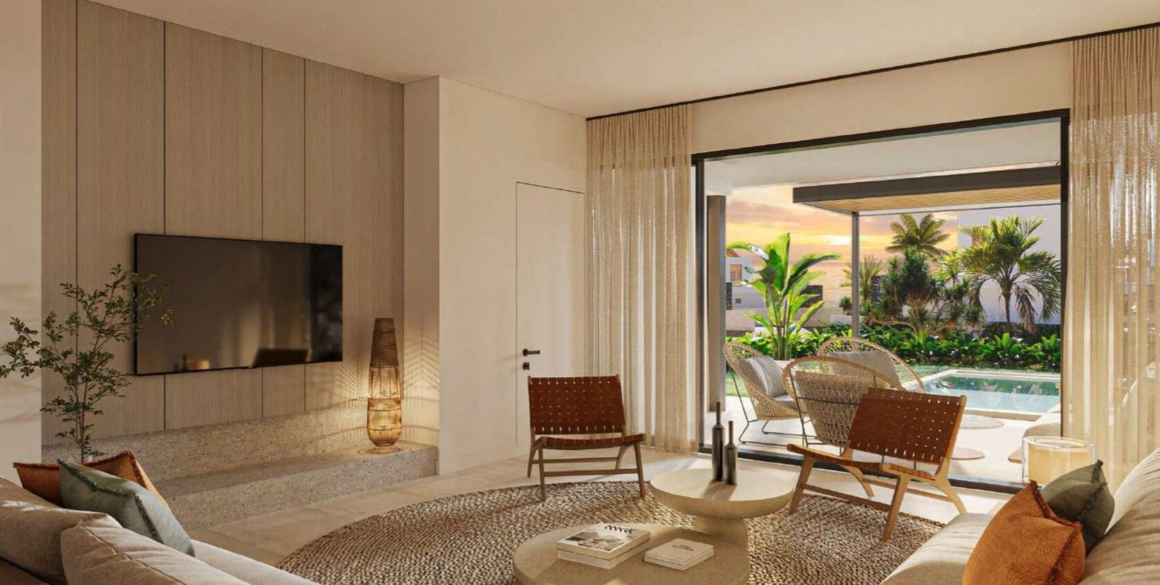 A modern living room with a flat-screen TV, a round coffee table, two wicker chairs, a sofa, and a view of a pool and palm trees through large windows.
