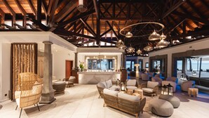 A spacious lobby with wicker furniture, a bar area, and large windows overlooking the ocean. - Maradiva Villas Resort & Spa (Flic-en-Flac)