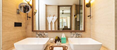 A bathroom with two large white sinks, a mirror, and wall sconces.