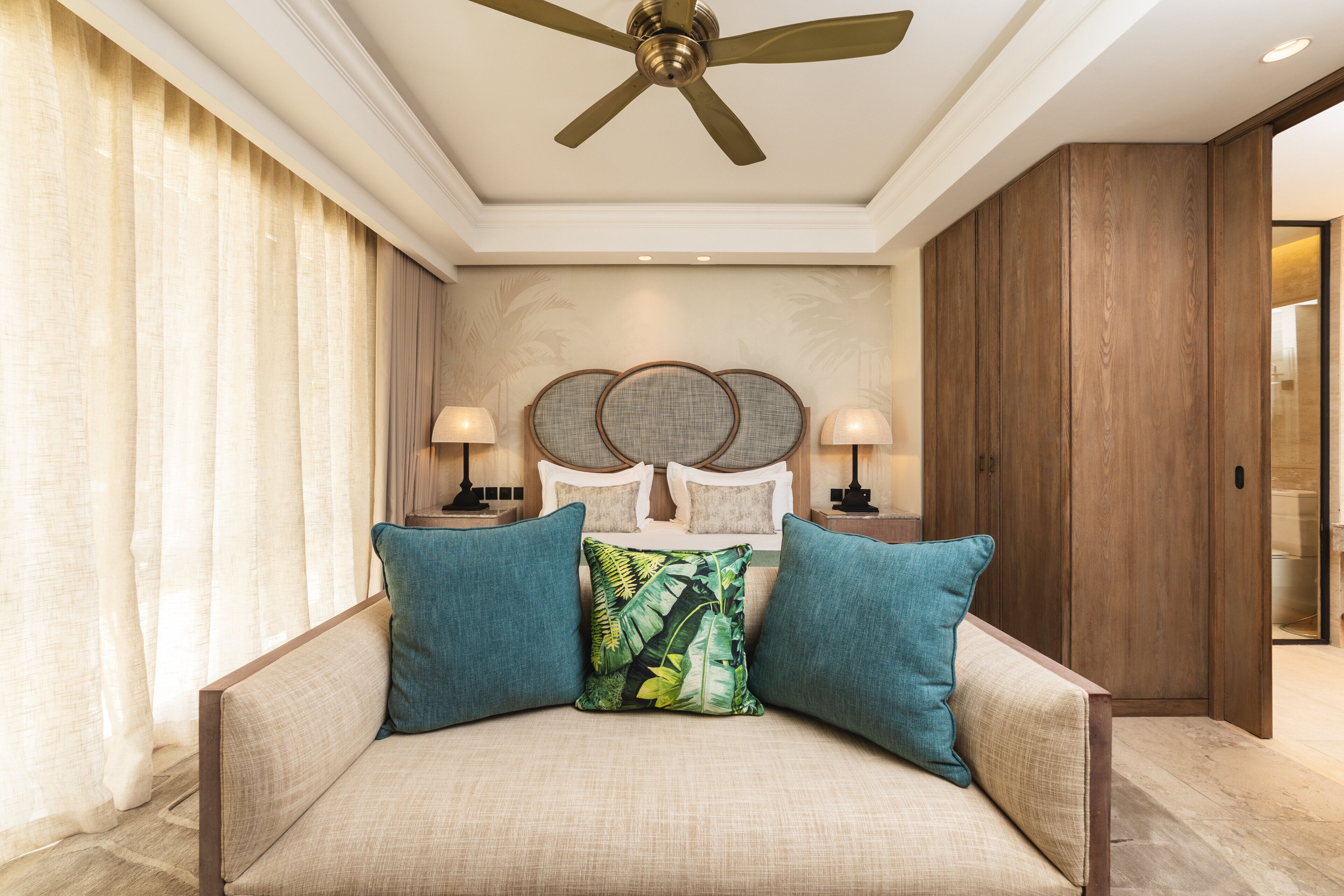 Un dormitorio con cama, ventilador de techo y mesita de noche con lámpara.