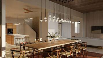 Un comedor moderno con una mesa y sillas de madera, lámparas colgantes esféricas y una cocina al fondo.