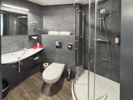 Un baño moderno con ducha acristalada, lavamanos blanco y retrete.