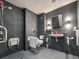 Un baño moderno con una pared de azulejos oscuros, un lavabo blanco, un inodoro y una zona de ducha.