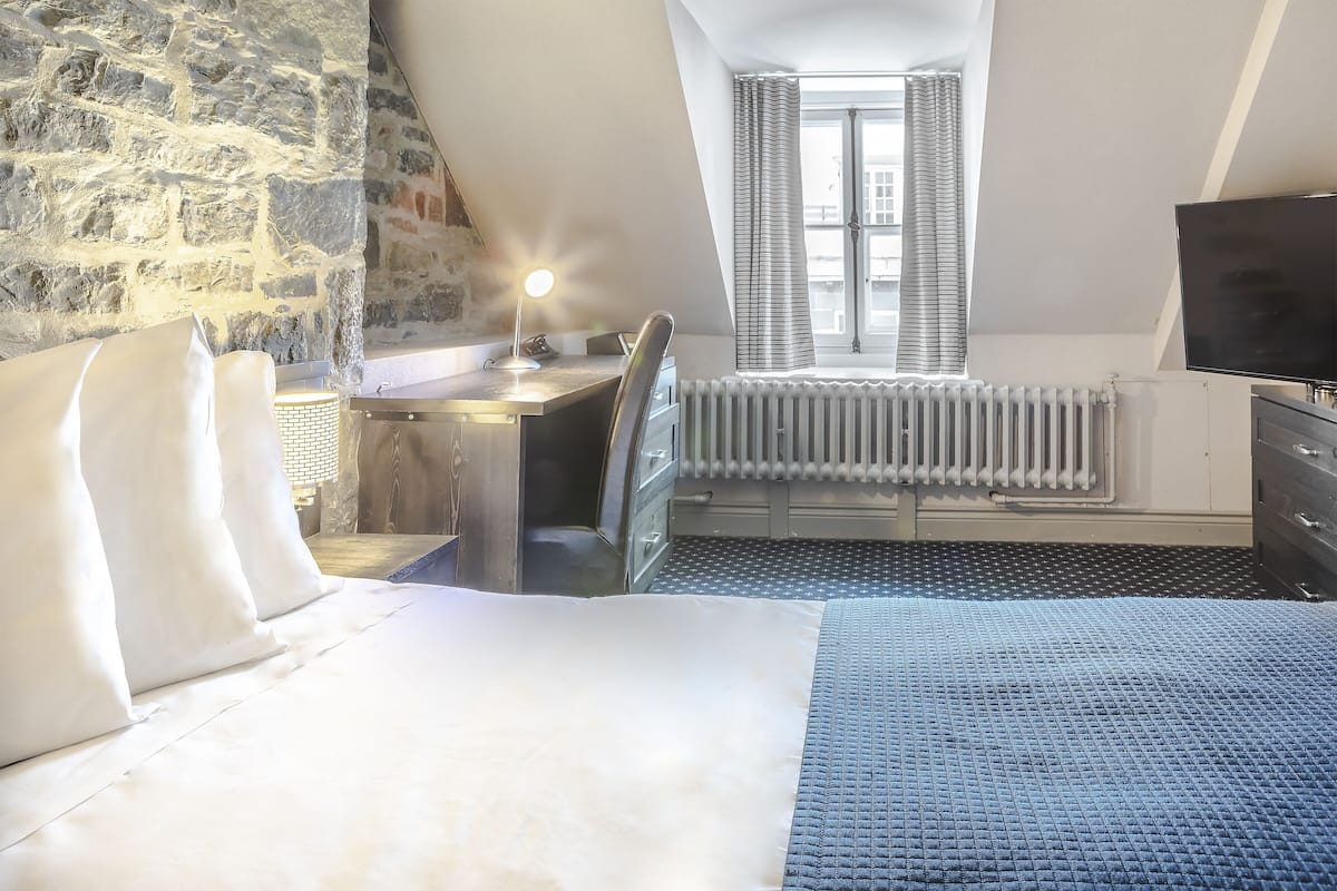 Une chambre à coucher avec un lit, un bureau, une chaise, un radiateur et un téléviseur.