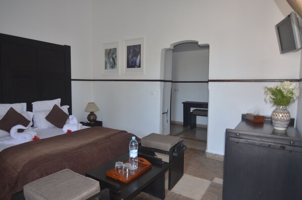 A hotel room with a bed, bedside table, and a small sitting area.