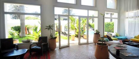 Un salón amplio con ventanas grandes, un espacio de descanso cómodo y vistas al jardín.
