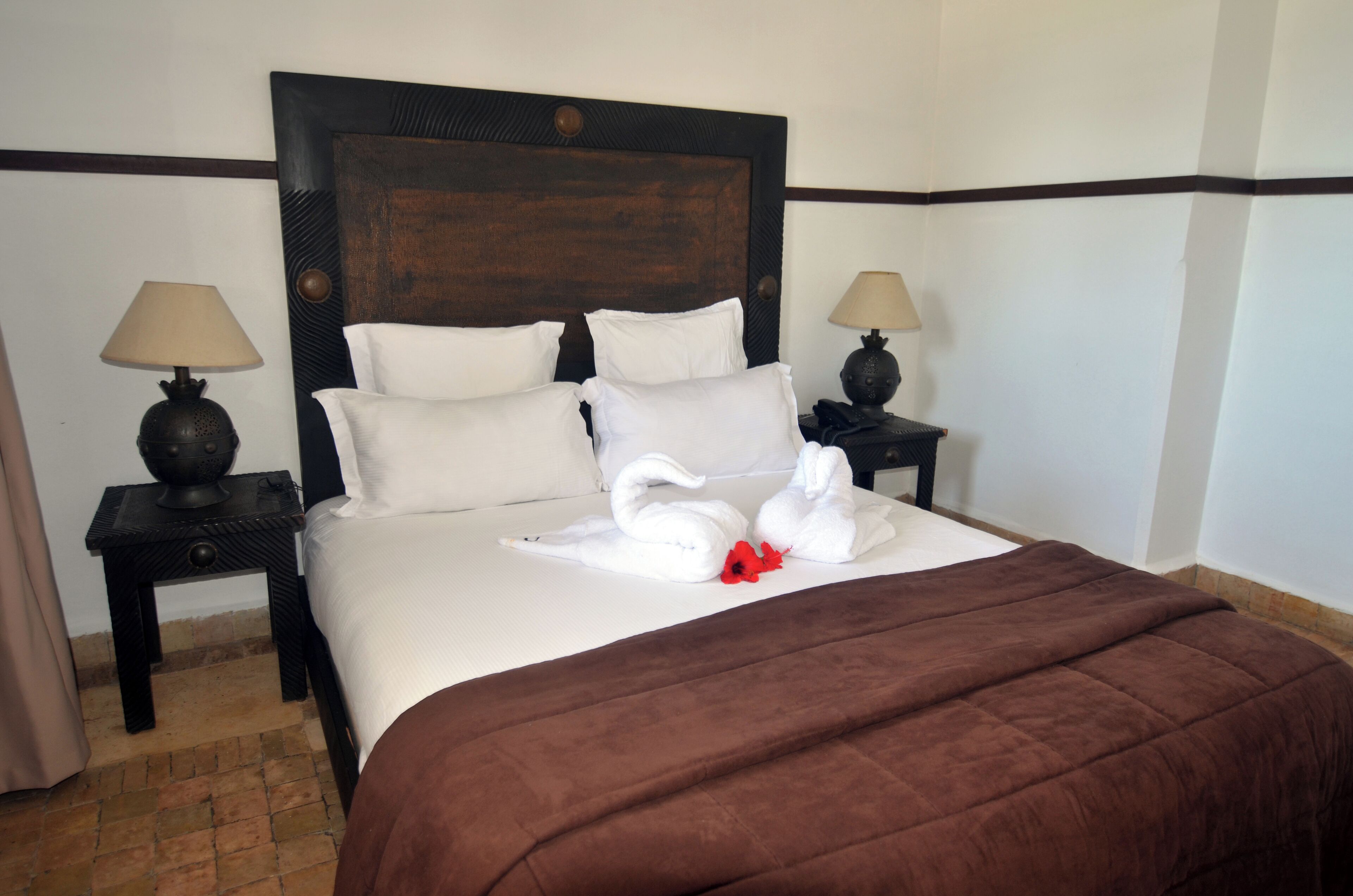 Ein Hotelzimmer mit einem großen Bett, zwei Nachttischen und einer braunen Bettdecke.
