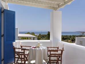 A terrace with a table set for two, overlooking a coastal view. - Aloni Hotel (Paros)