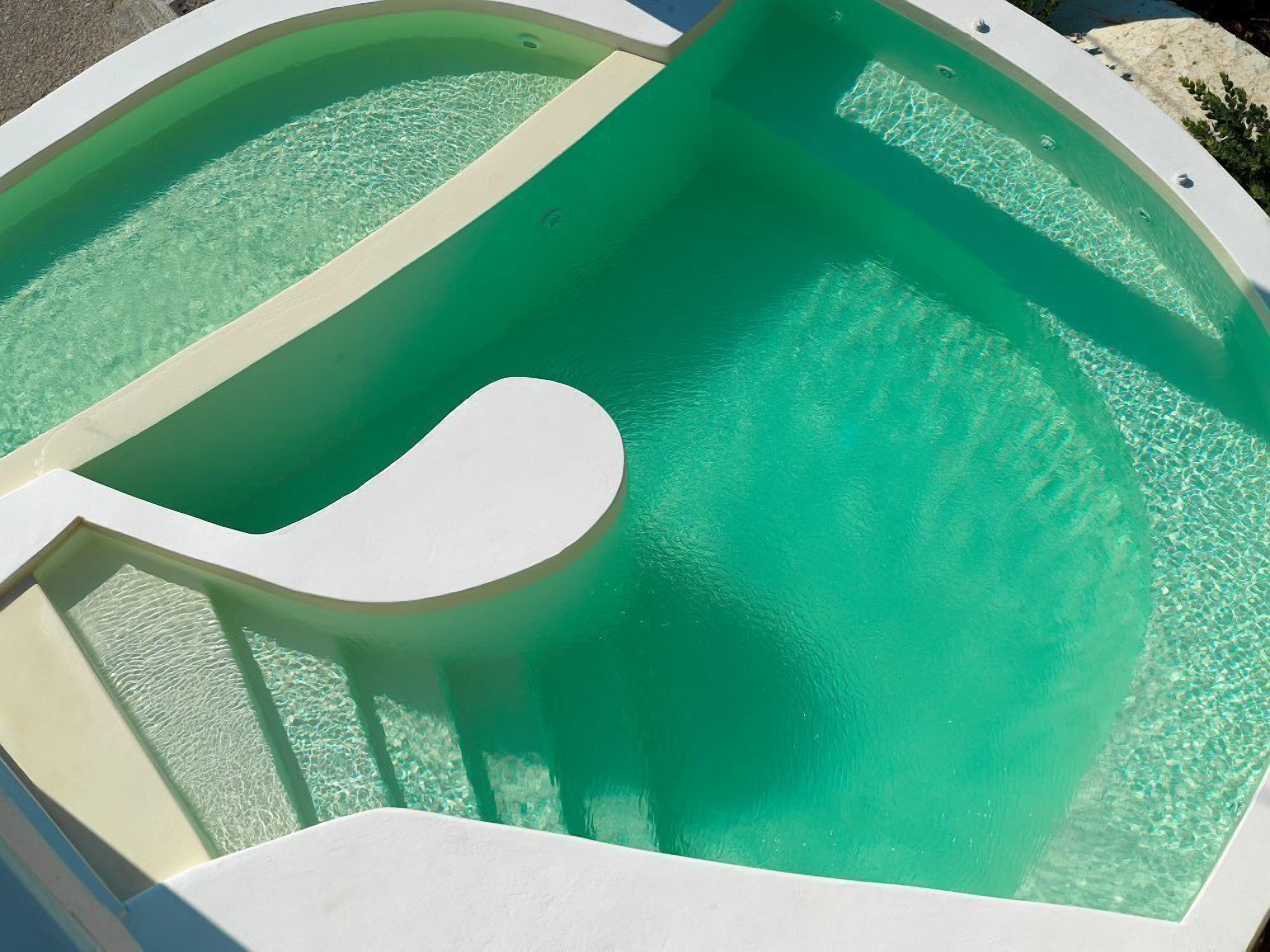 Una piscina con superficie de agua cristalina y borde blanco curvo.