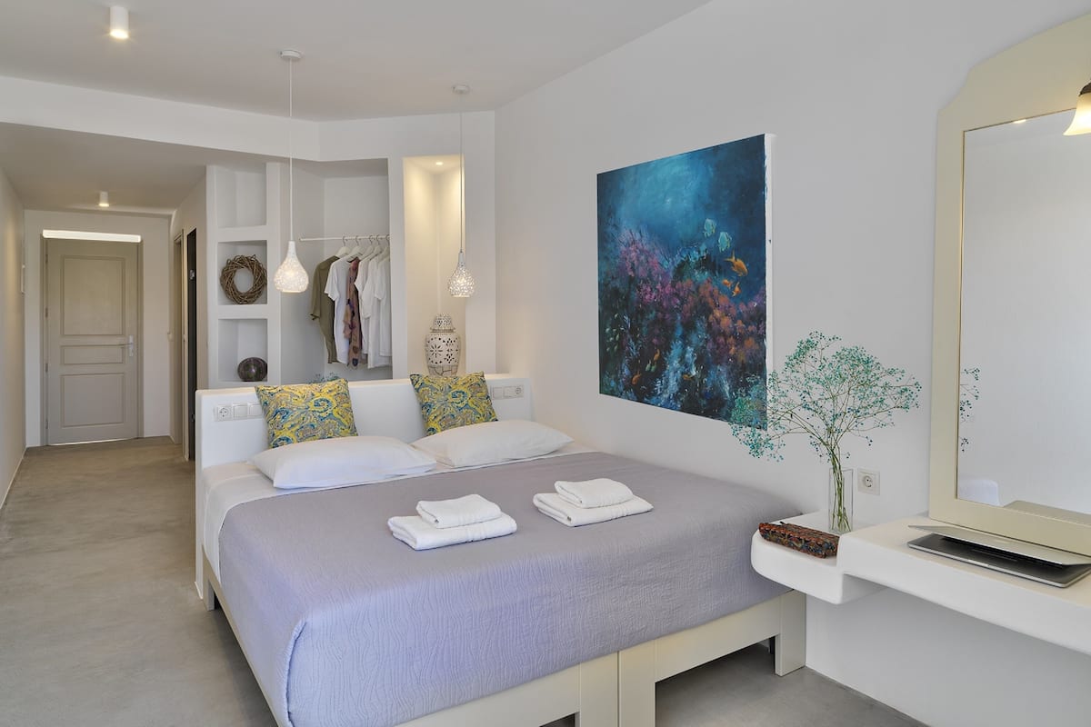 A modern bedroom with a bed, bedside tables, a large painting, and a mirror.