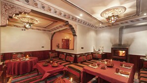 Un comedor tradicional con chimenea, manteles rojos y cojines estampados.