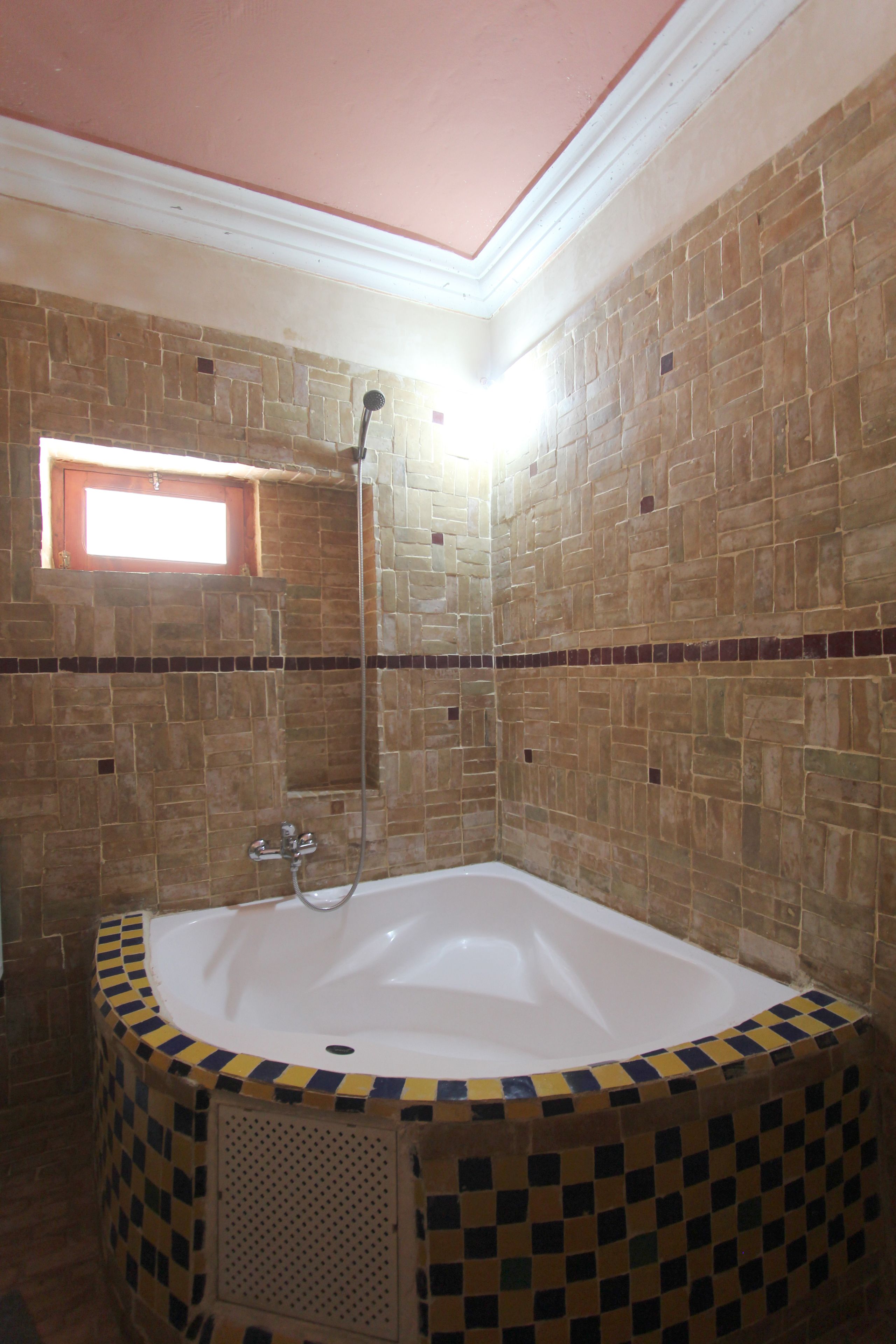 A bathroom with a bathtub, shower, and tiled walls.